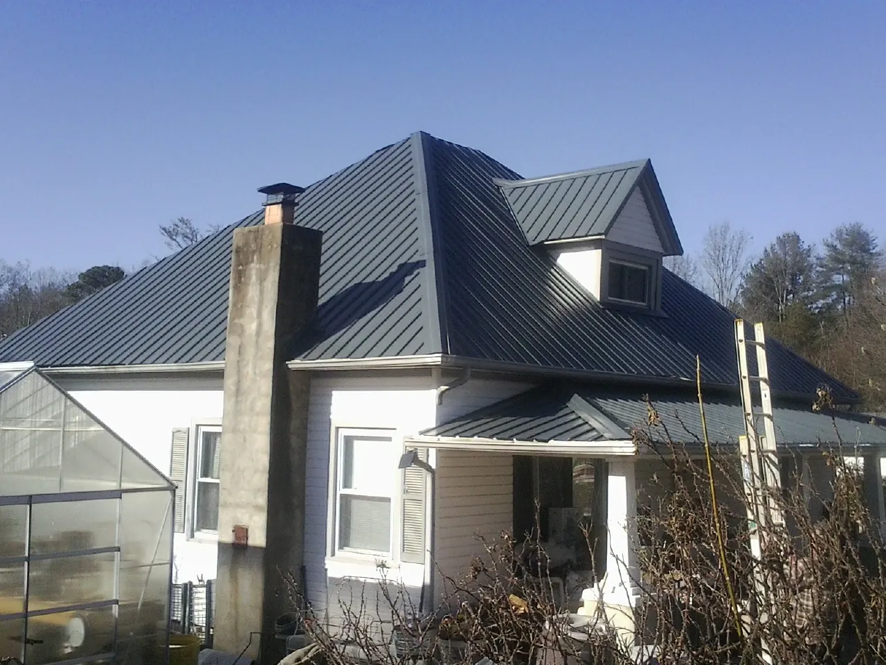 Dark blue standing seam metal roof on a white farmhouse with dormer — Slate & Tile Roof Repair by Roofing Brothers in Larwill
