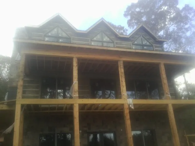 Dormers and porch framing on a large log home under construction — Roof Coating work by our crew in Larwill