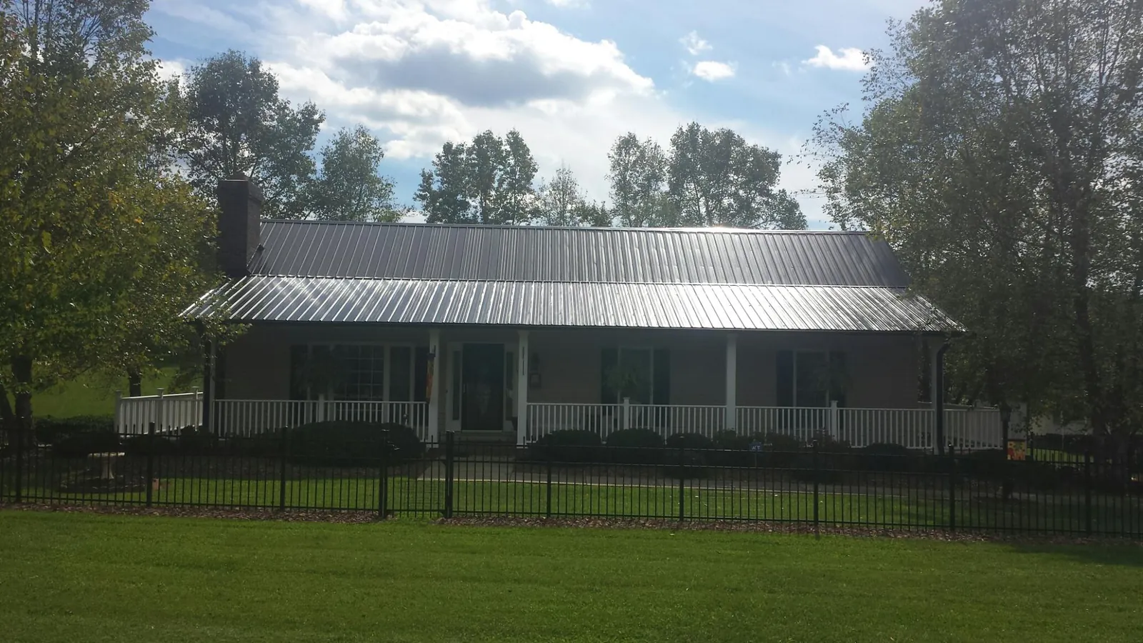 Gray metal roof on a brick ranch with a full width front porch — Gutter Guard Installation work by our crew in Larwill