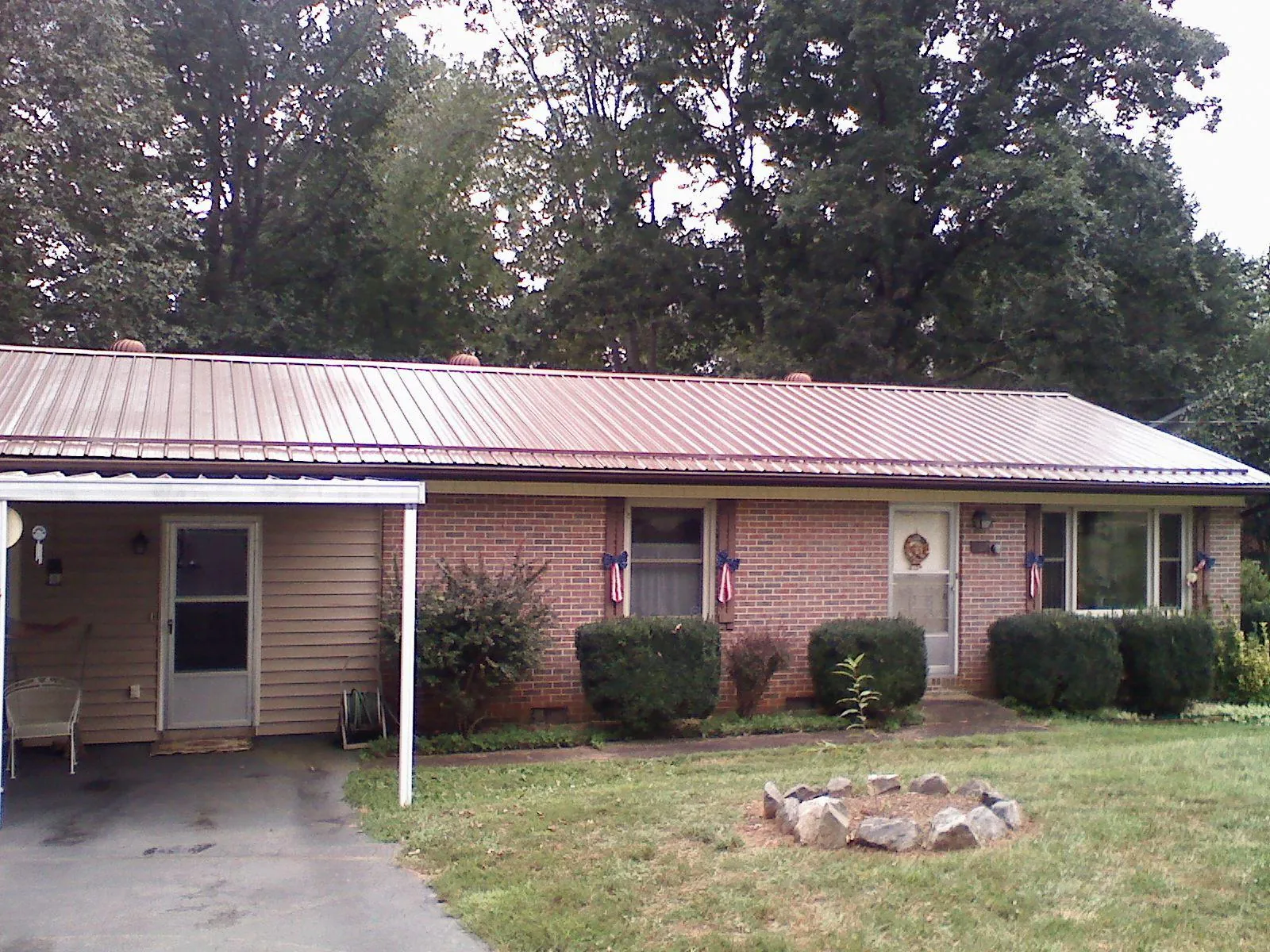 Bronze metal roof and carport on a brick ranch home — Roof Repair work by our crew in Larwill